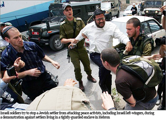Israeli soldiers try to stop a Jewish settler from attacking peace activists, including Israeli left-wingers, during Israeli-settler-1.jpg