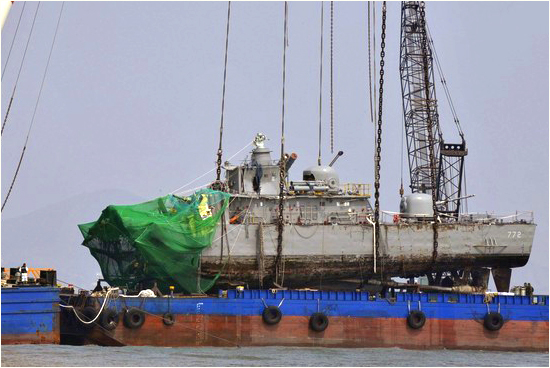 Salvage team members and rescue workers put a part of a sunken naval vessel on a barge after they lifted it with a giant crane, off Baengnyeongdo island near the maritime border with North Korea, northwest of Seoul, April 15, 2010 Korea-incident.jpg