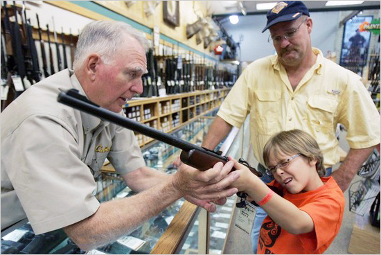 Hunter McConathy (C), 7, holds a hunting rifle with a short stock as his father Bryan (R) and Cabela's salesman Russ Duncan (L) watch him at the Cabela's store in Fort Worth, Texas June 26, 2008. Individual Americans have a right to own guns, the Supreme Court ruled on Thursday for the first time in history, striking down a strict gun control law in the U.S. capital. americans_guns_550.jpg