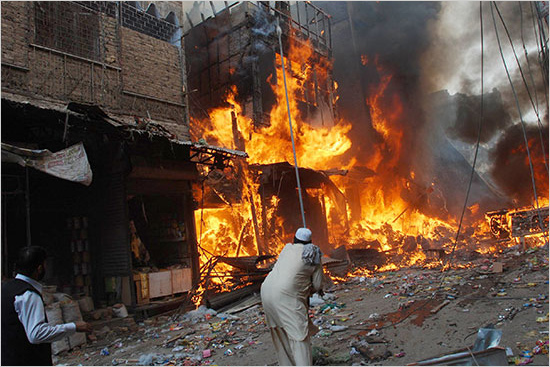 Fire fighters extinguish fire while people survey at the site of bomb explosion, in Peshawar located in Pakistan's restive North West Frontier Province October 28, 2009. A car bomb killed 57 people and wounded about 100 on Wednesday in a crowded market in the Pakistani city of Peshawar, government officials said, the latest in a series of bloody militant attacks. blackwater_pakistan_550.jpg