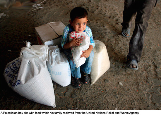 A Palestinian boy sits with food which his family recieved from the United Nations Relief and Works Agency for Palestinian refugees (UNRWA) at the al Shatea refugee camp in Gaza City. An Israeli security committee is to decide to increase restrictions on moving fuel and goods into the Gaza Strip and threatened to cut off electricity in reaction to launching makeshift rockets from the enclave in to Israel. gaza_food.jpg