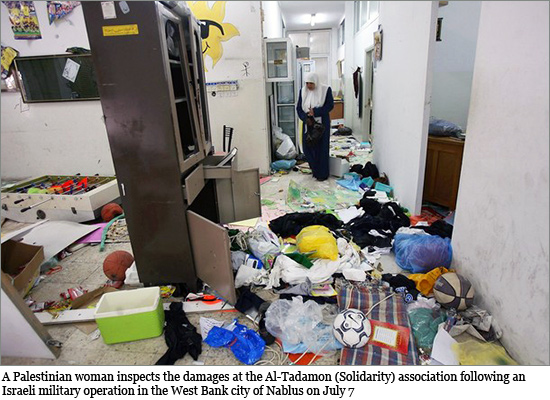 A Palestinian woman inspects the damages at the Al-Tadamon (Solidarity) association following an Israeli military operation in the West Bank city of Nablus on July 7, 2008 nablus_550.jpg